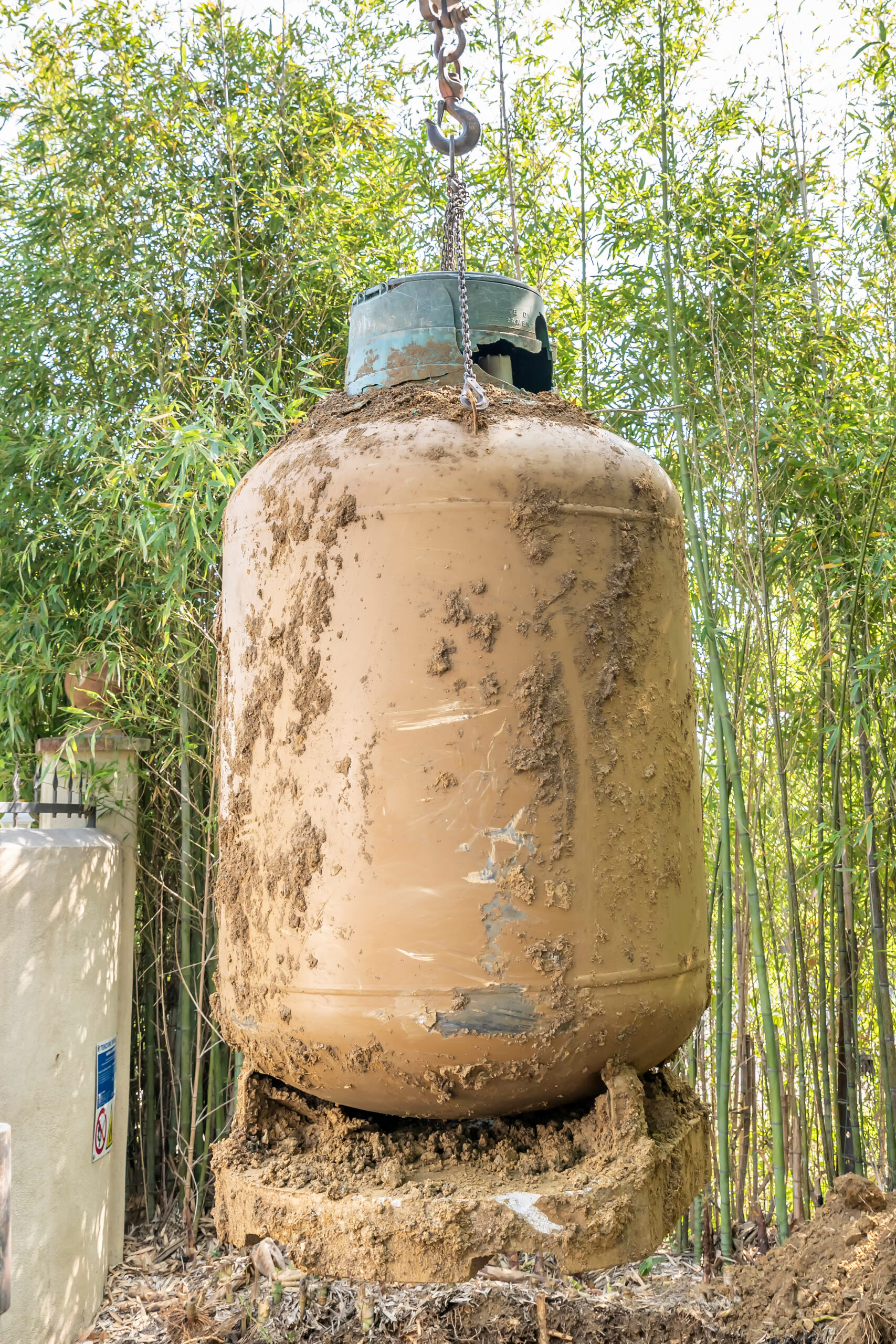 An old underground LPG tank is removed by lifting it with a crane